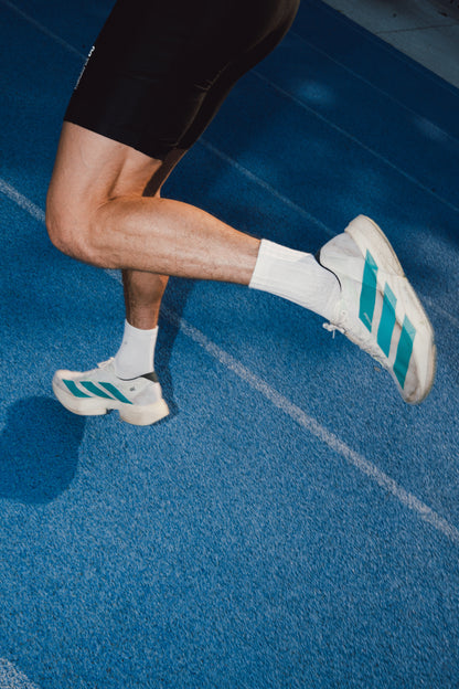 Runner wearing PAIRR The 400 crew performance running socks on a blue athletics track