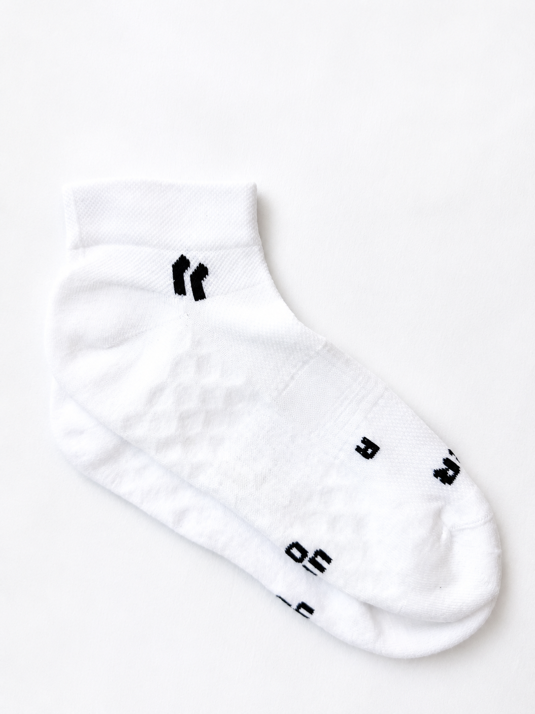 White PAIRR “Stride” ankle socks photographed on a clean white background, featuring a lightweight low-cut silhouette, breathable textured knit zones, and black logo detailing for a minimal performance-inspired look.