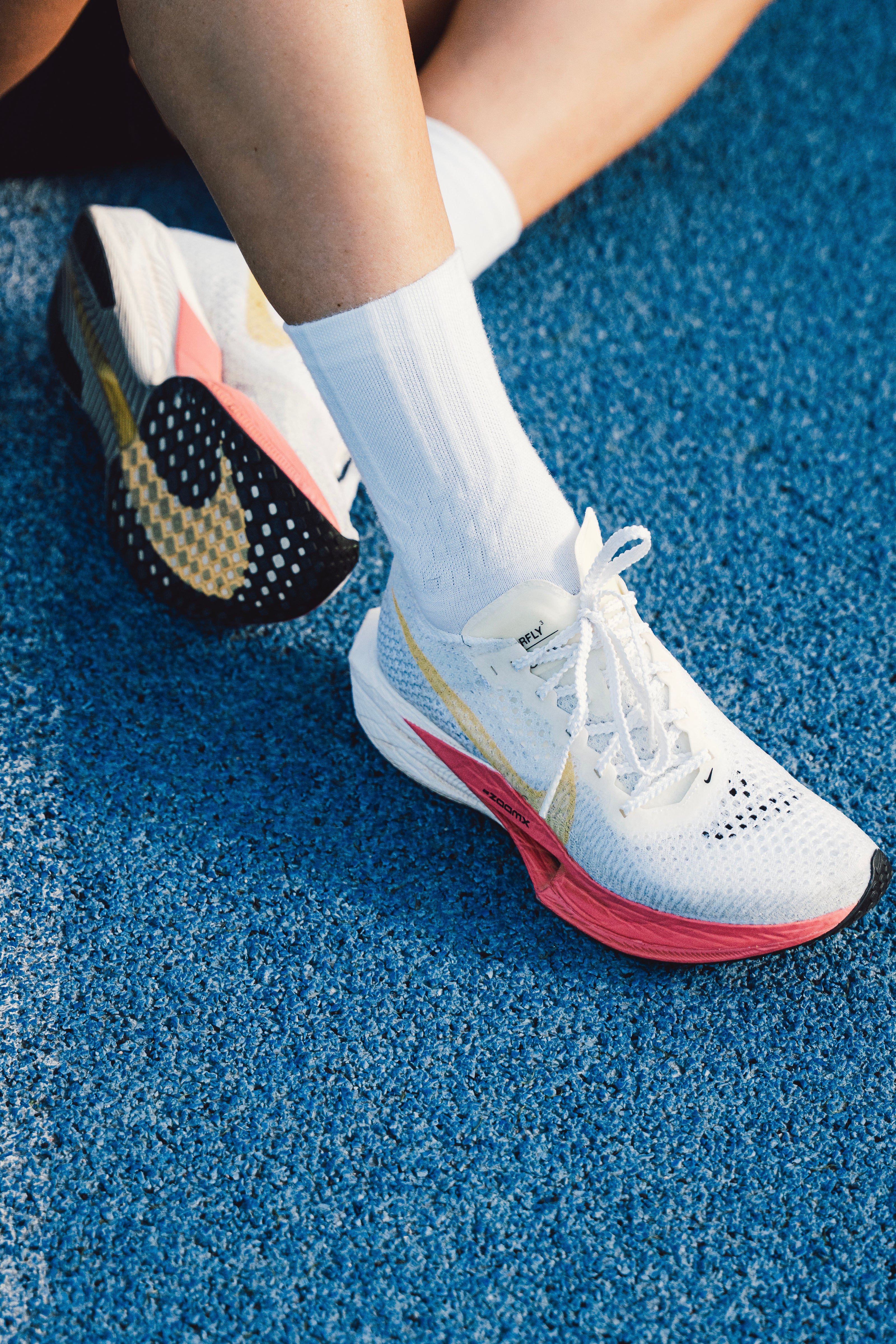 Person wearing colorful running shoes on a blue track surface